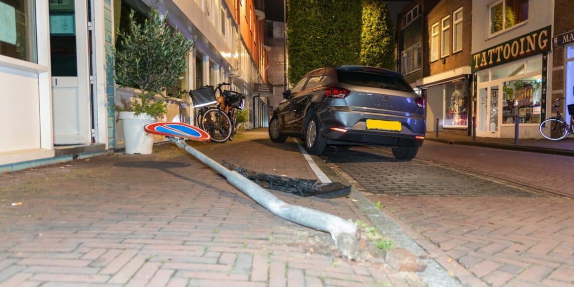 Auto ramt geparkeerde auto en verkeersbord in Amsterdamstraat