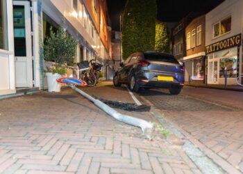 Auto ramt geparkeerde auto en verkeersbord in Amsterdamstraat